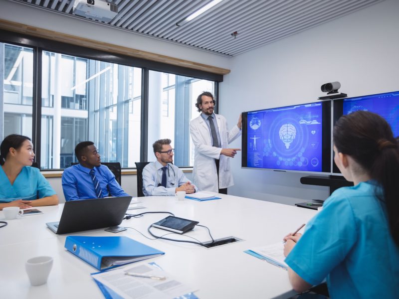 Doctor giving presentation to team of interim doctors at conference room